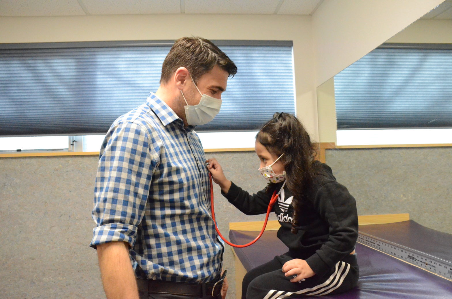 A child plays doctor to Physician Assistant Brian Mills heart